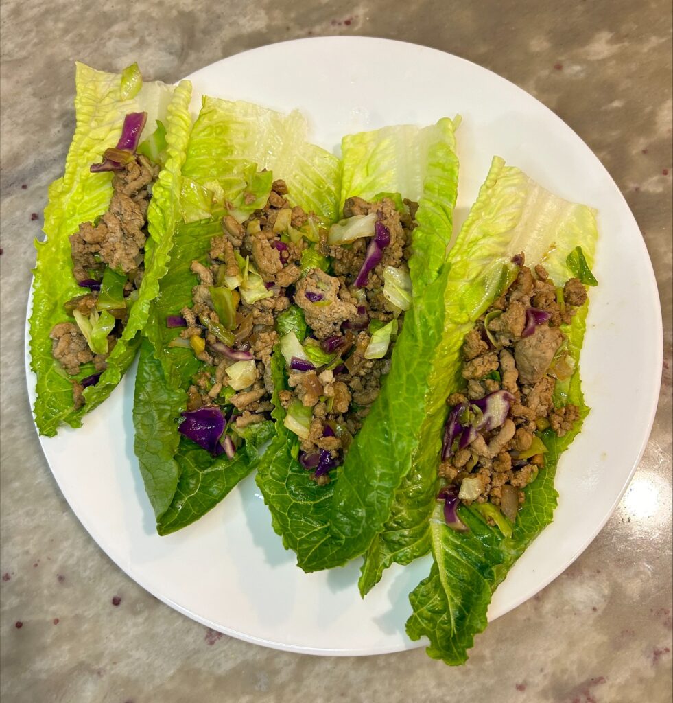 4 lettuce wraps with the filling in them on a plate